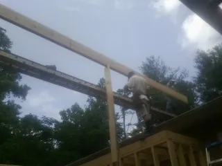 Carpenter setting a ridge beam over a new addition frame — Ice Dam Removal by Roofing Brothers in Elberon