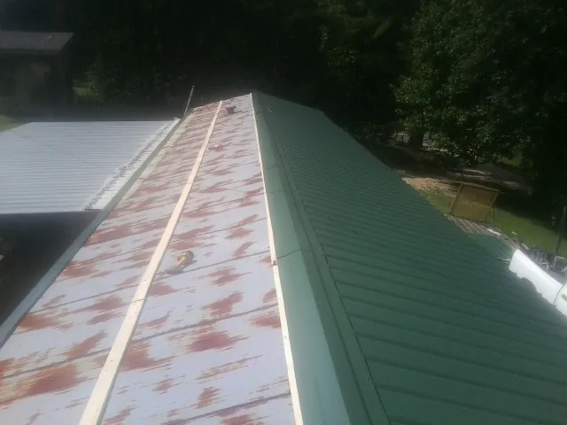 Old rusted panels beside newly installed green metal roofing — Wind Damage Roof Repair by Roofing Brothers in Elberon