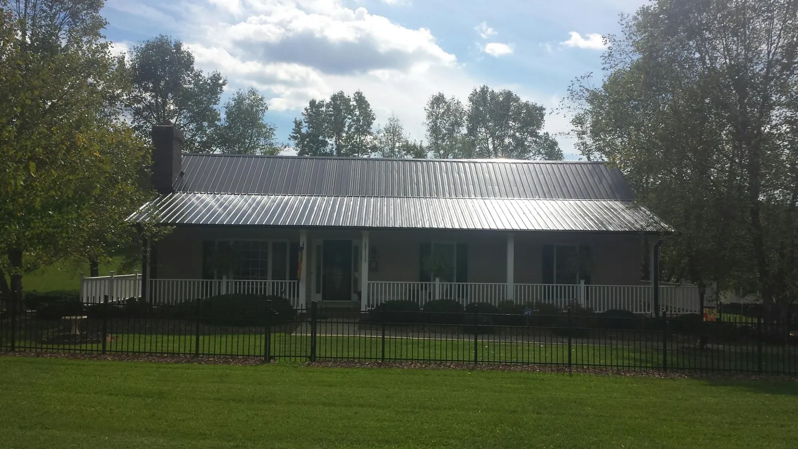 Gray metal roof on a brick ranch with a full width front porch — Gutter Guard Installation work by our crew in Elberon