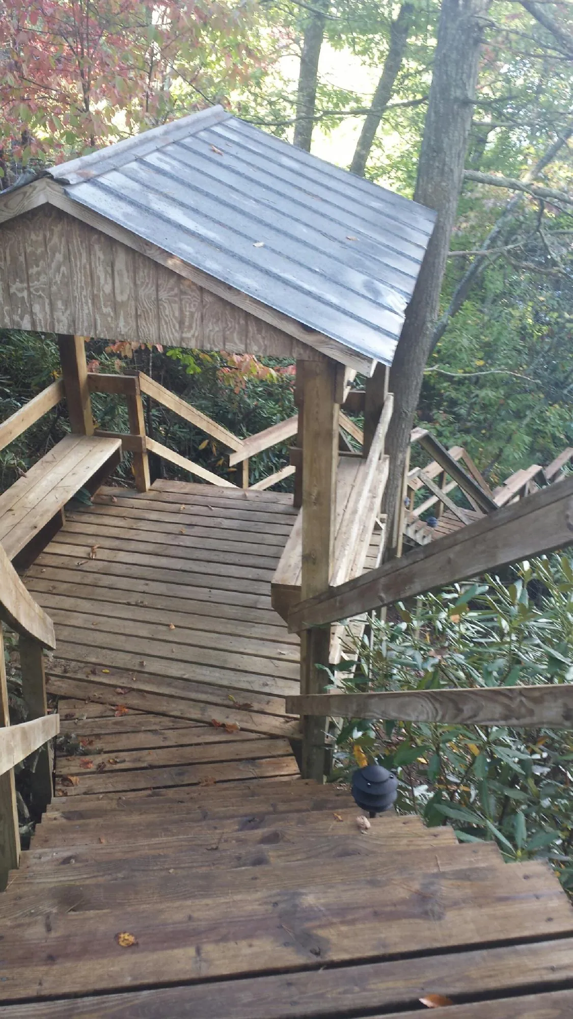 Metal roofed shelter over wooden steps on a wooded walkway — Skylight Repair & Installation work by our crew in Elberon