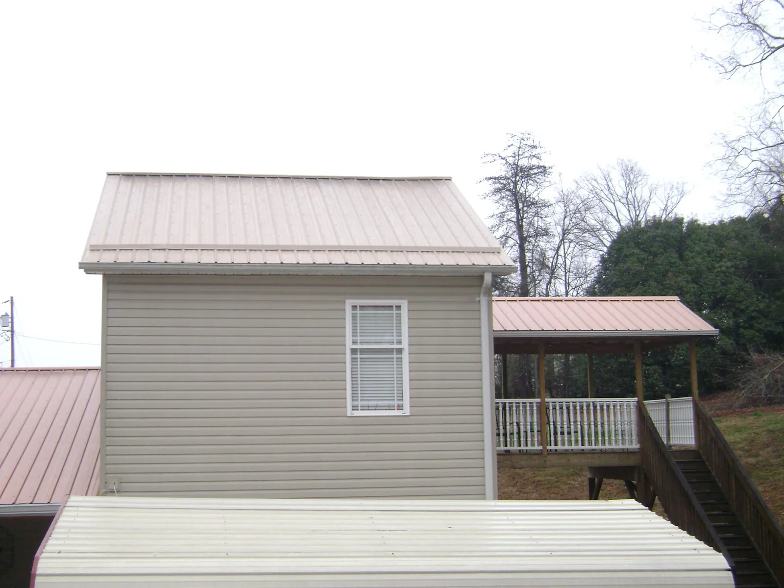 Tan metal roofs on a two story addition and attached porch, from a Roof Replacement job in Elberon