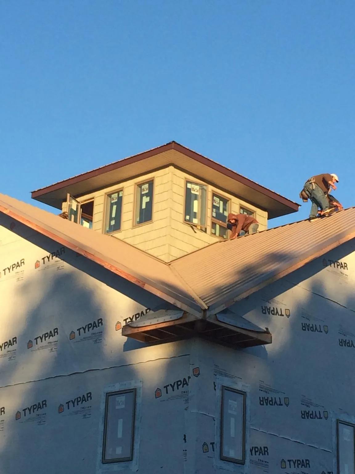 Roofers working around a rooftop cupola on a new metal roof at sunset — Roof Waterproofing in Elberon by Roofing Brothers